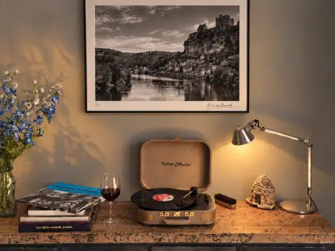 Een platenspeler, boeken en een glas rode wijn onder een zwart-witfoto van de Dordogne